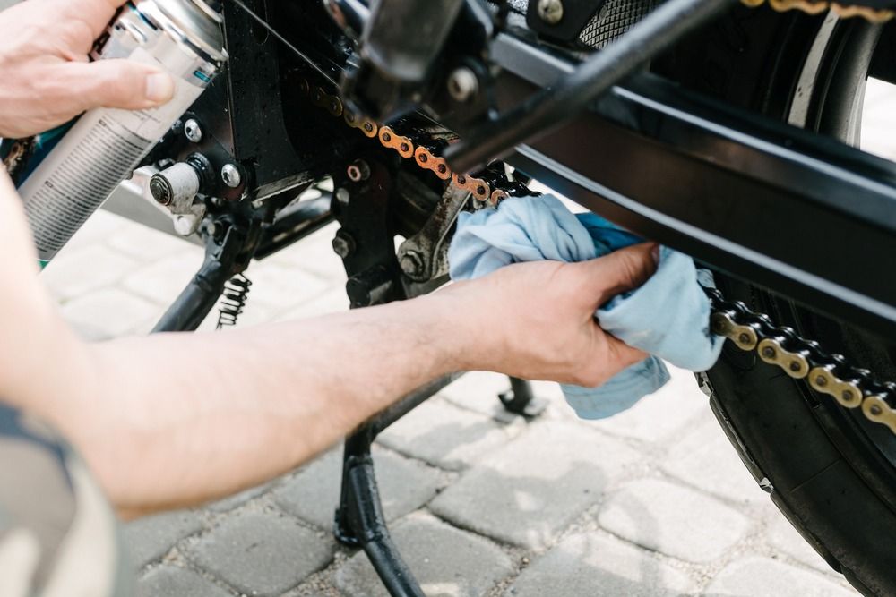 manos de mecanico engrasando cadena de moto